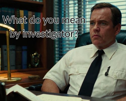 Investigator sits with hands folded on the desk.